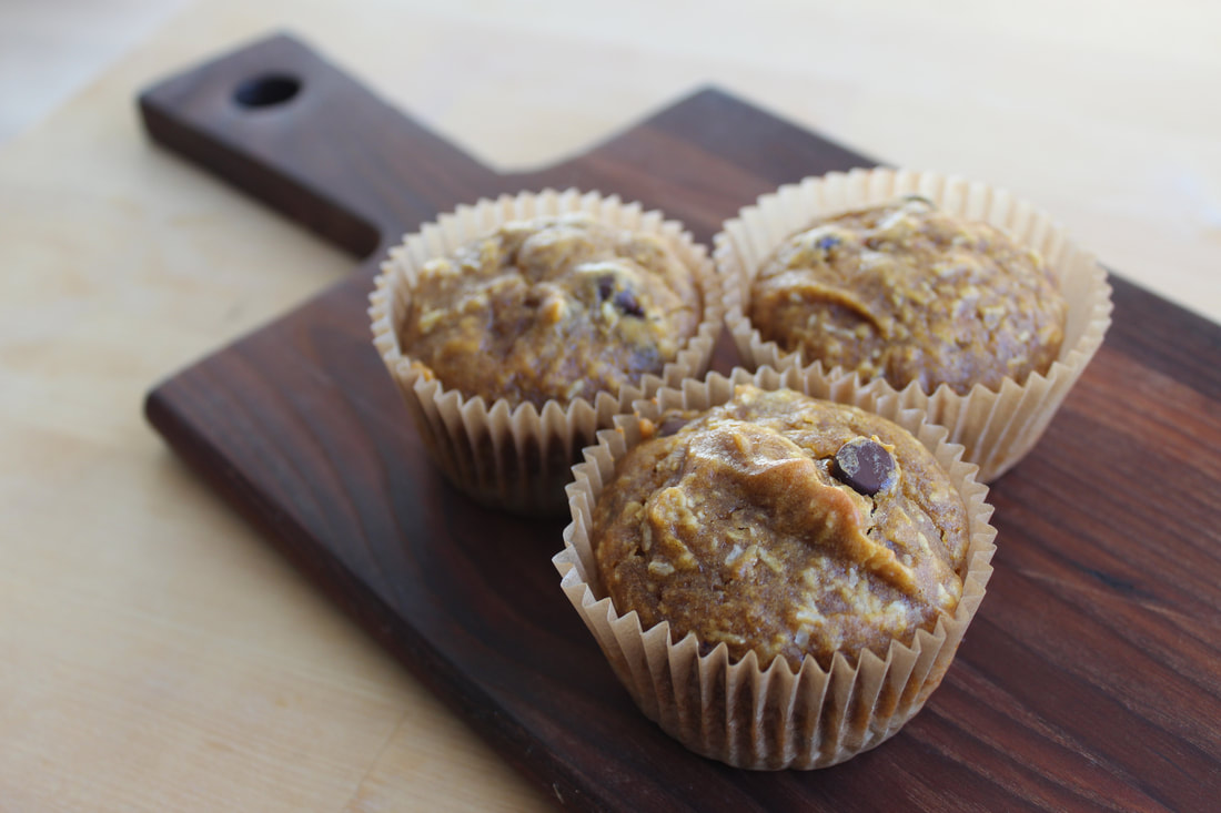 Three banana pumpkin muffins on a wood board.
